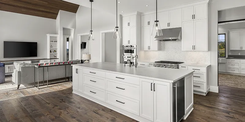Fully remodeled custom open-concept kitchen in Massachusetts featuring a large island, custom white cabinetry, and modern pendant lighting.